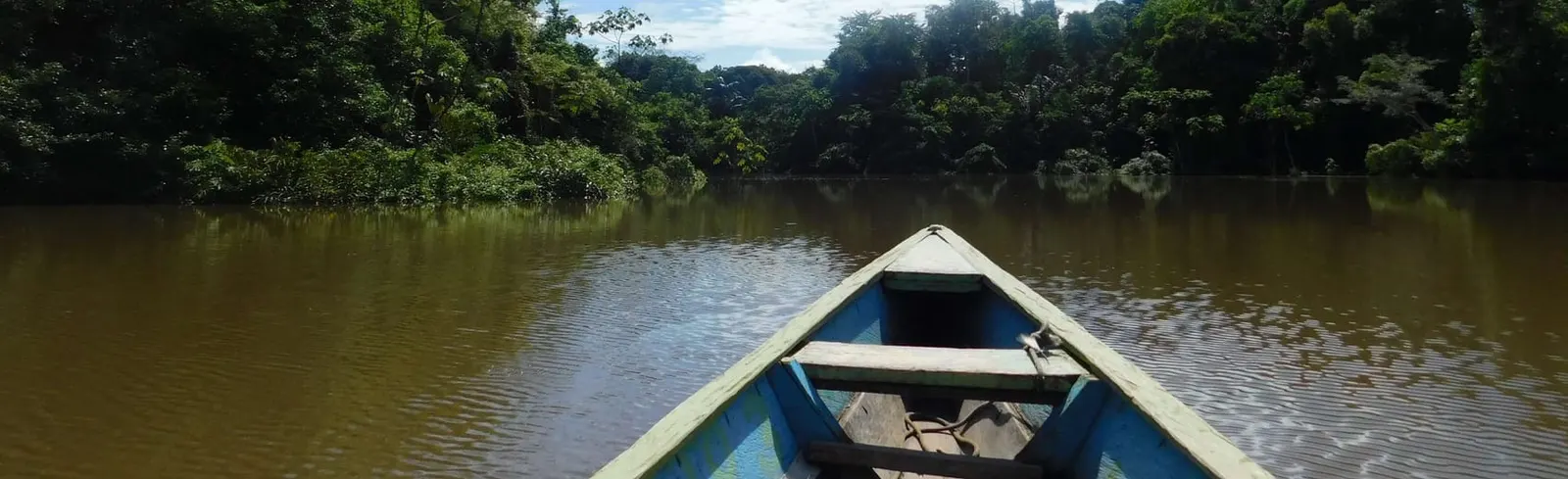 Wooden dugout canoe floating on the brown water of the Amazon River in Colombia