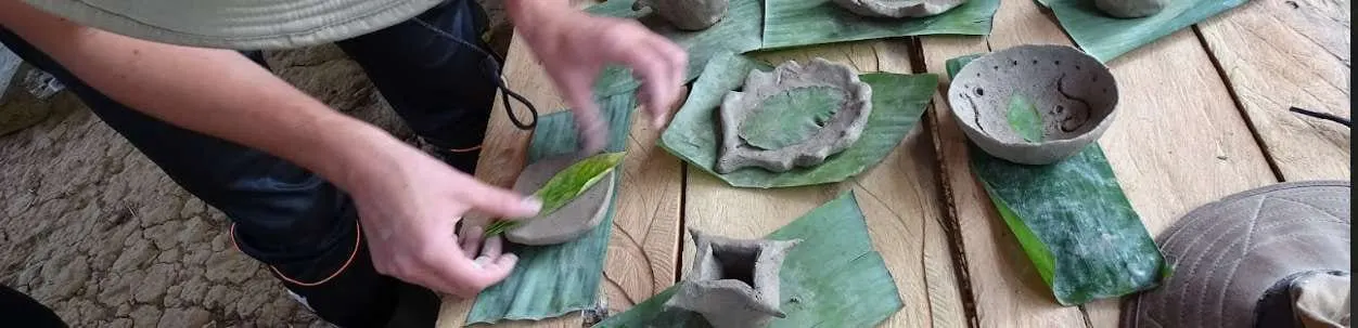 Manos moldeando cerámica de barro sobre hojas en un taller Ticuna