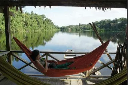 Mujer descansando en una hamaca sobre un lago tranquilo del Amazonas