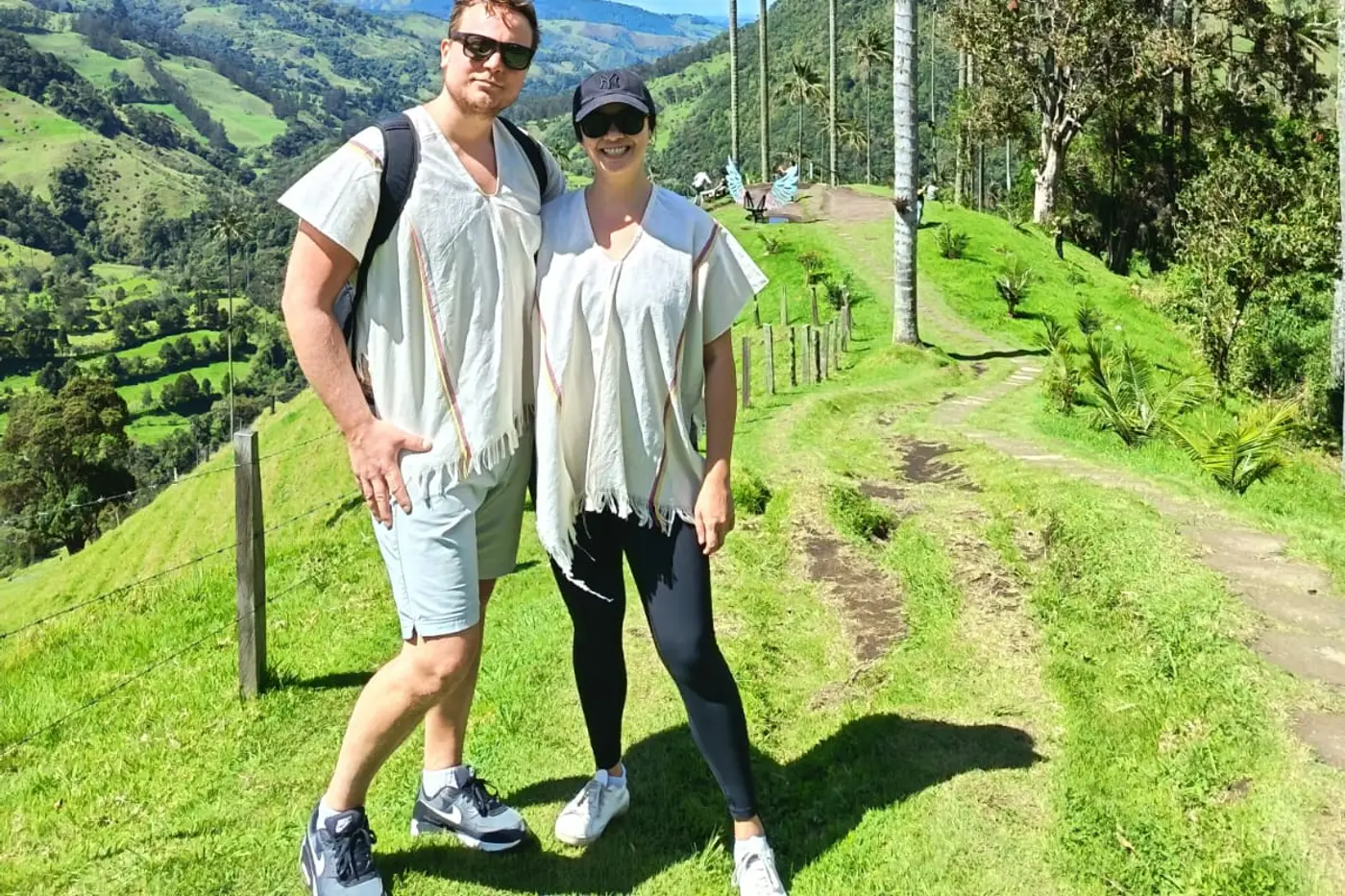 Couple posing on a trail with wax palms behind them in the Cocora Valley