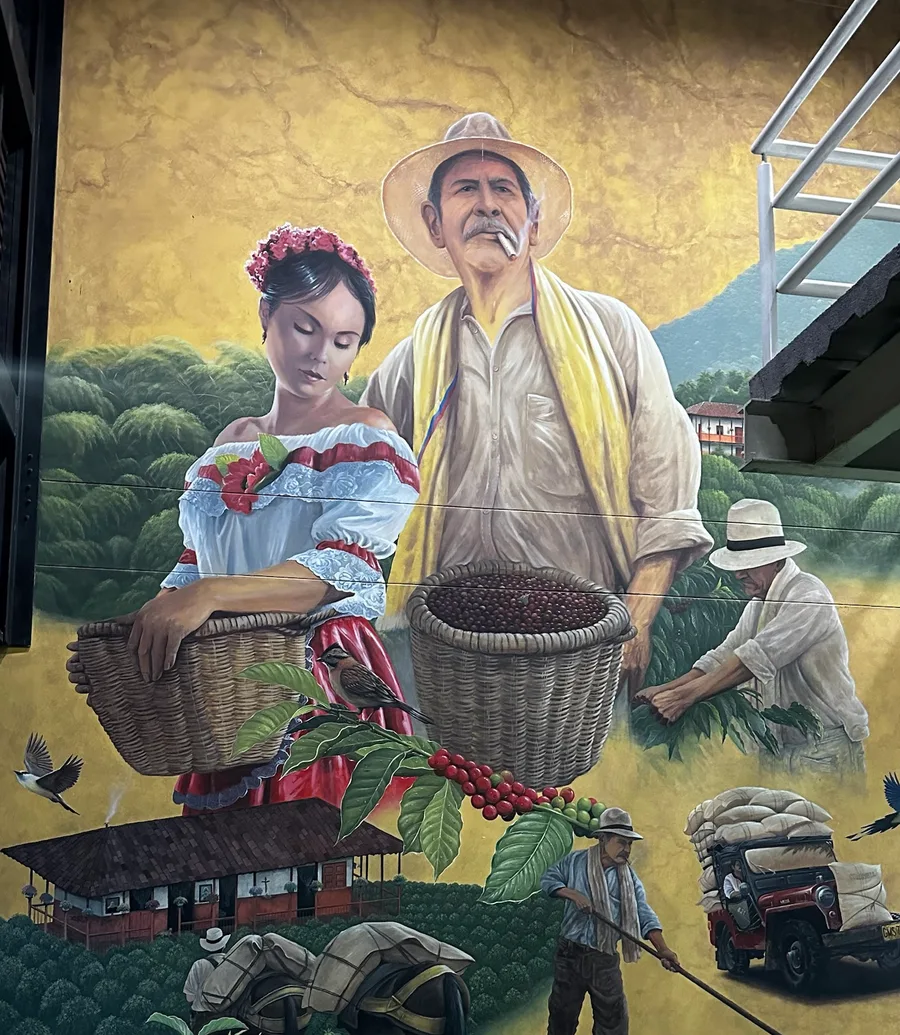 Mural of coffee growers carrying baskets of coffee cherries, with a farmhouse, a mule and a jeep loaded with sacks