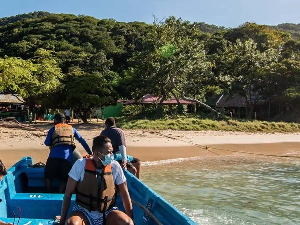 Travelers in a boat in front of a Tayrona beach