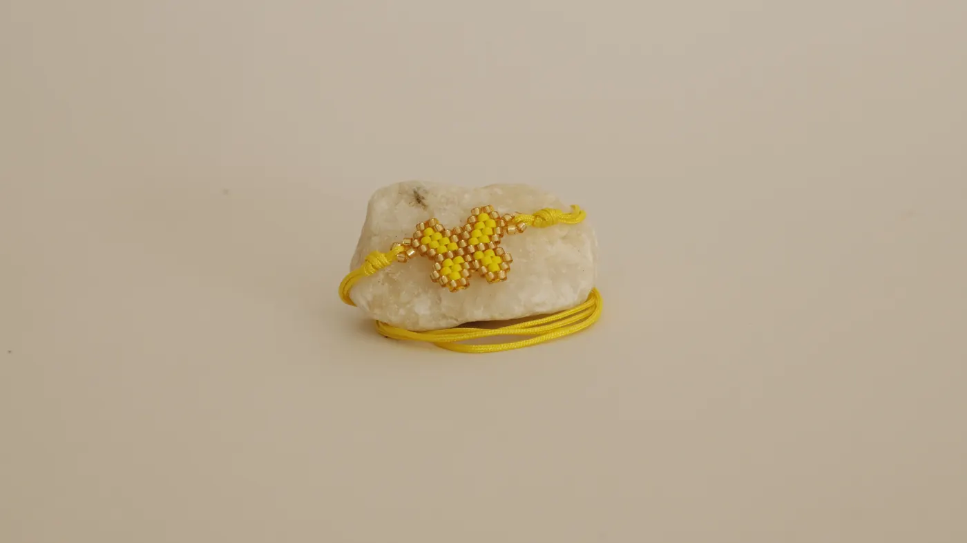 Yellow beaded butterfly bracelet resting on a stone