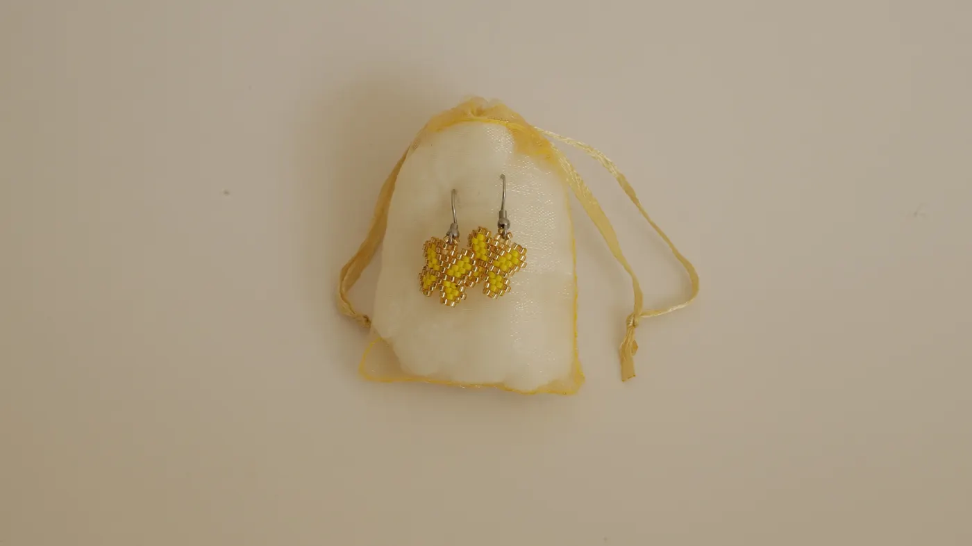 Butterfly earrings inside a yellow organza bag