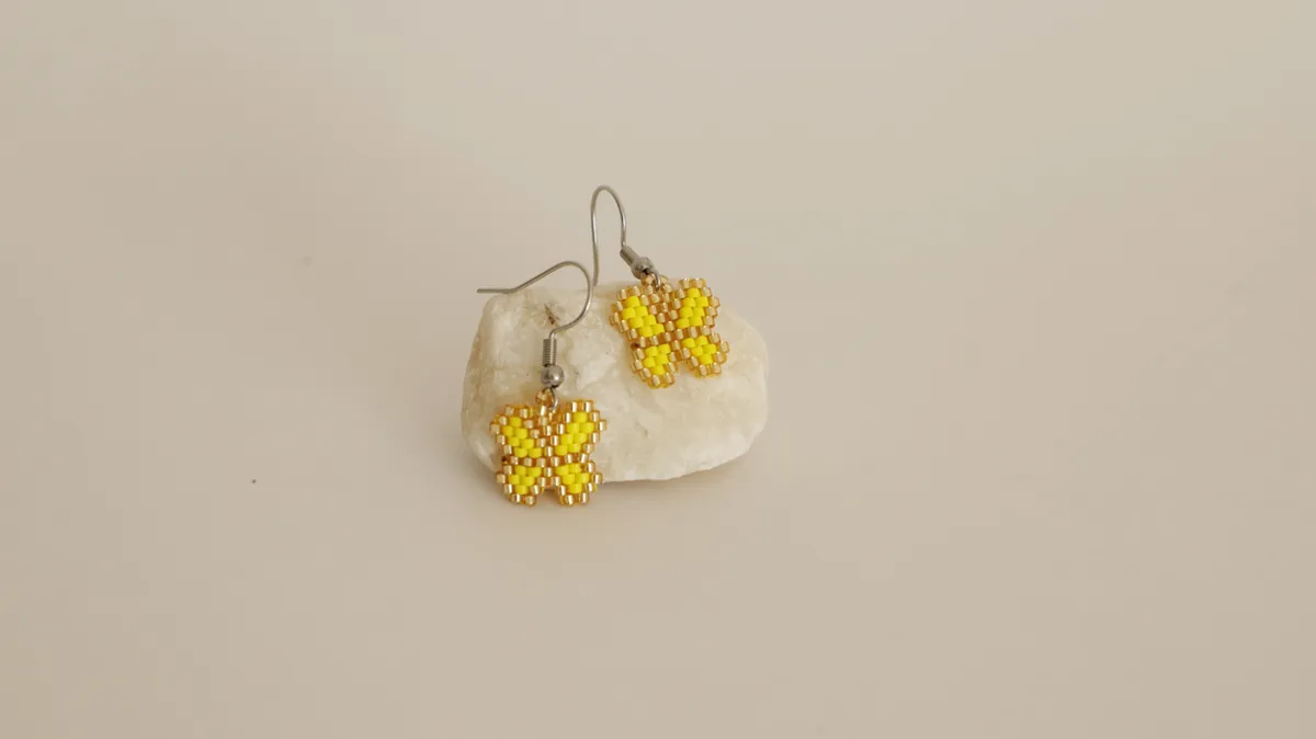 Yellow butterfly earrings resting on a stone