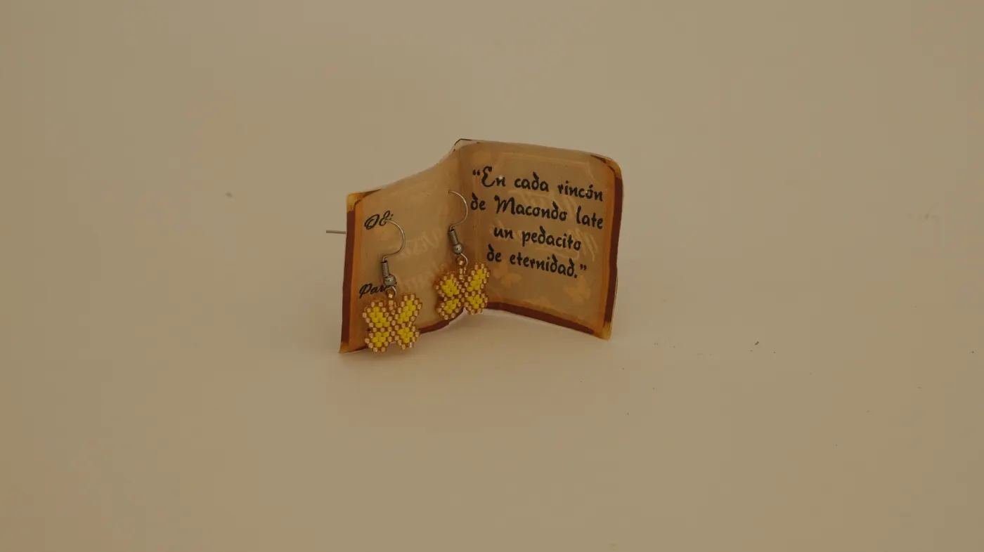 Earrings presented in a small Macondo-themed book