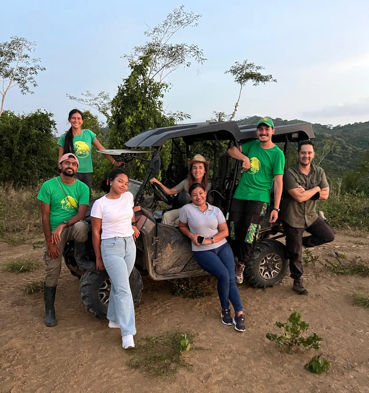 Group of visitors in green shirts posing next to a UTV