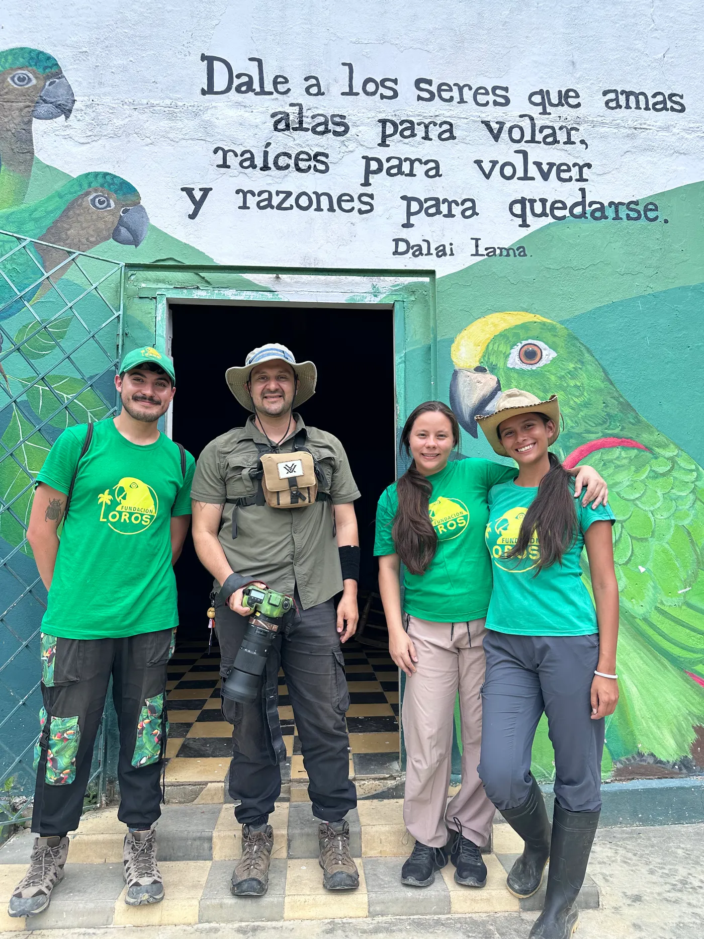 Staff and visitors in green shirts in front of a parrot mural