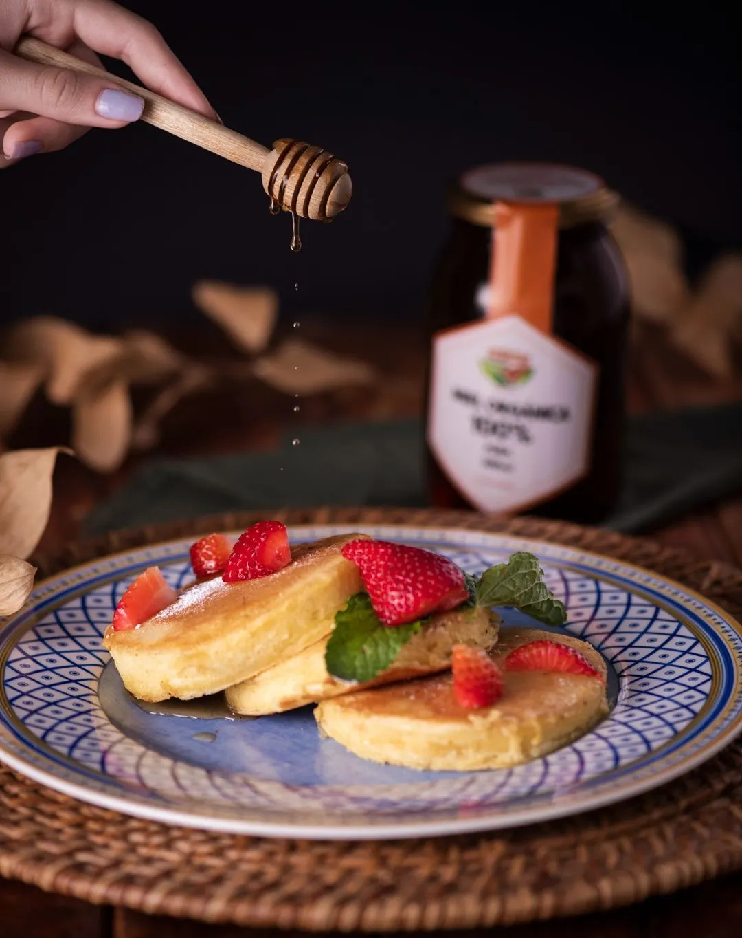 Pancakes with strawberries and honey on a ceramic plate