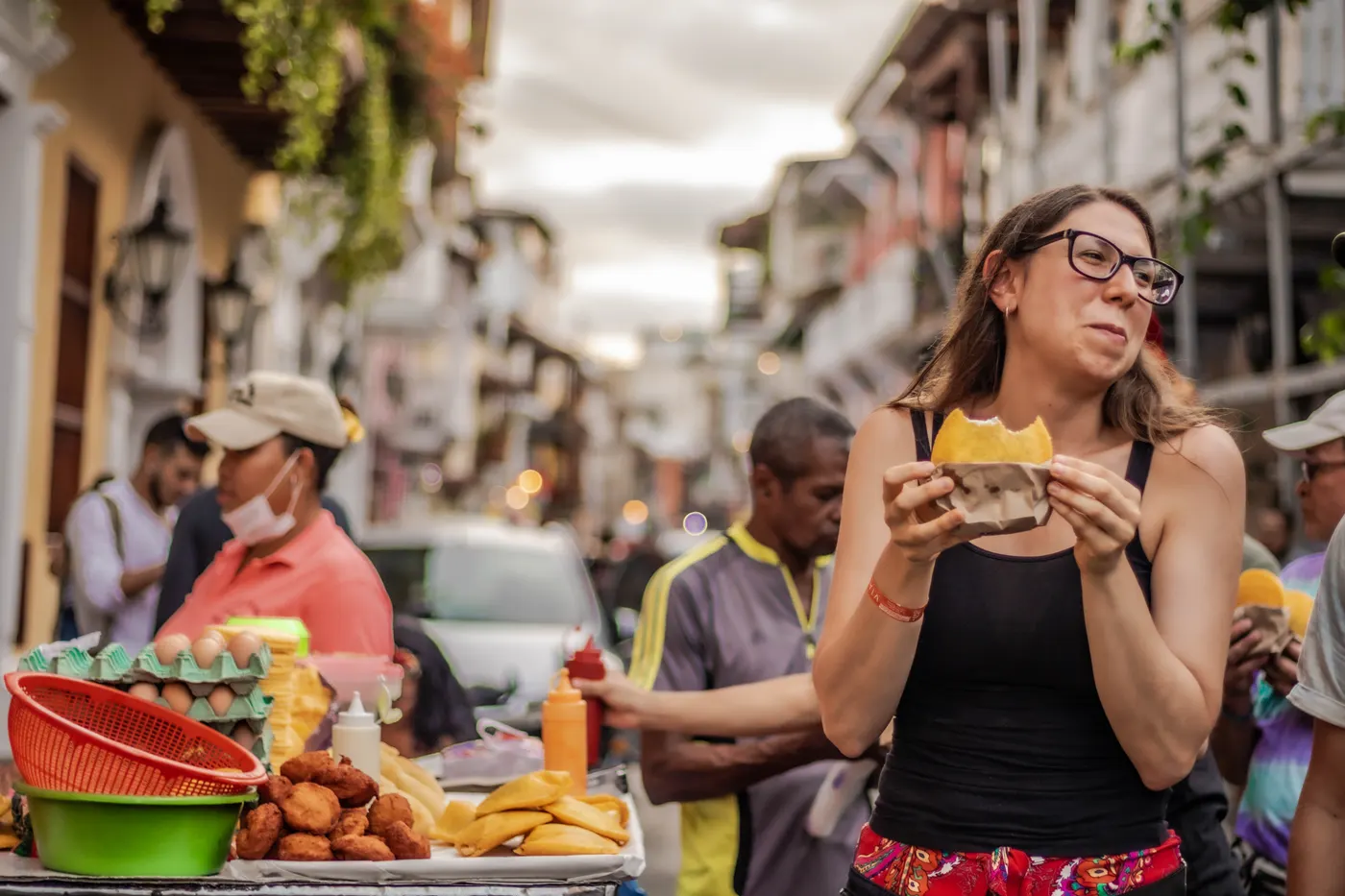 A visitor tasting street food on a colonial street in Cartagena