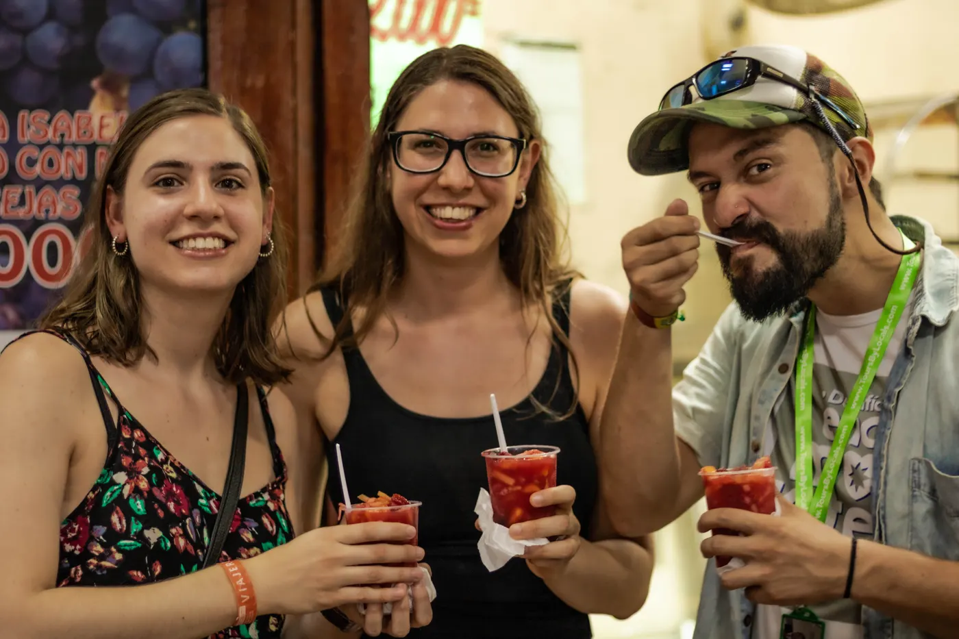 Three friends holding red drinks on the street food tour