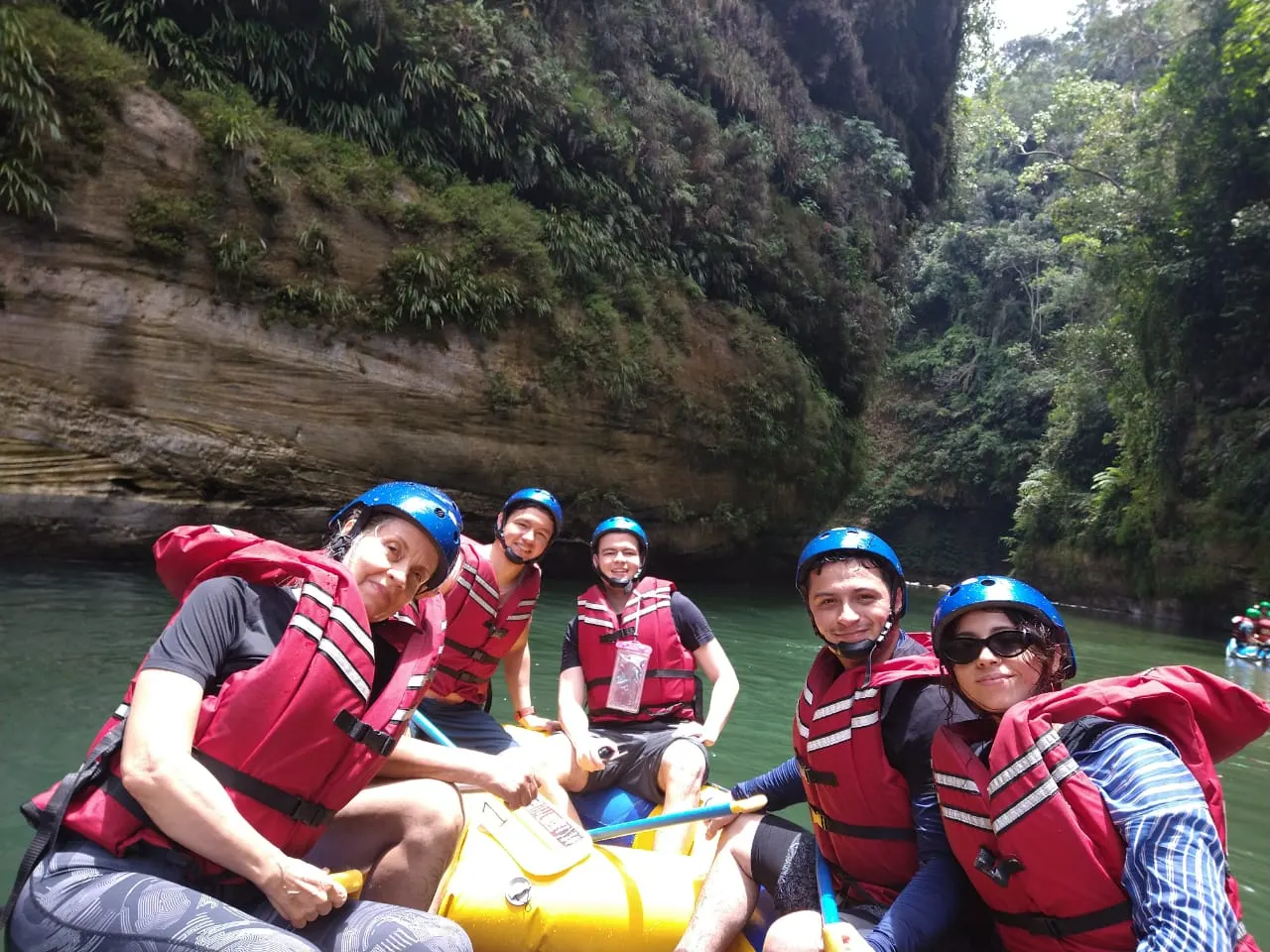 Rafters in helmets and life jackets inside a canyon