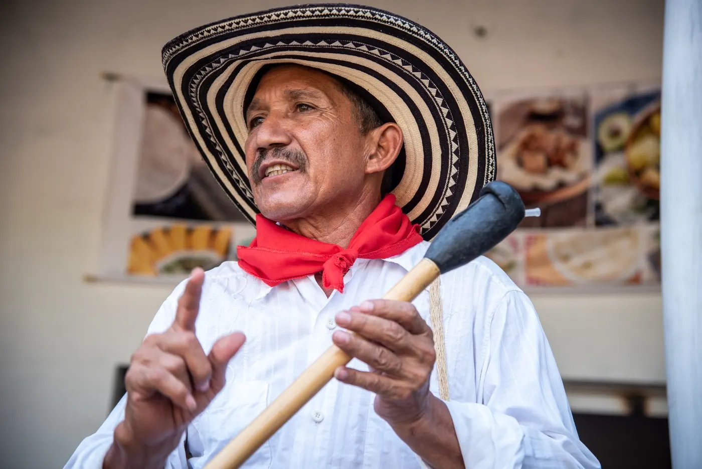 Local man in a sombrero vueltiao and red scarf gesturing as he speaks