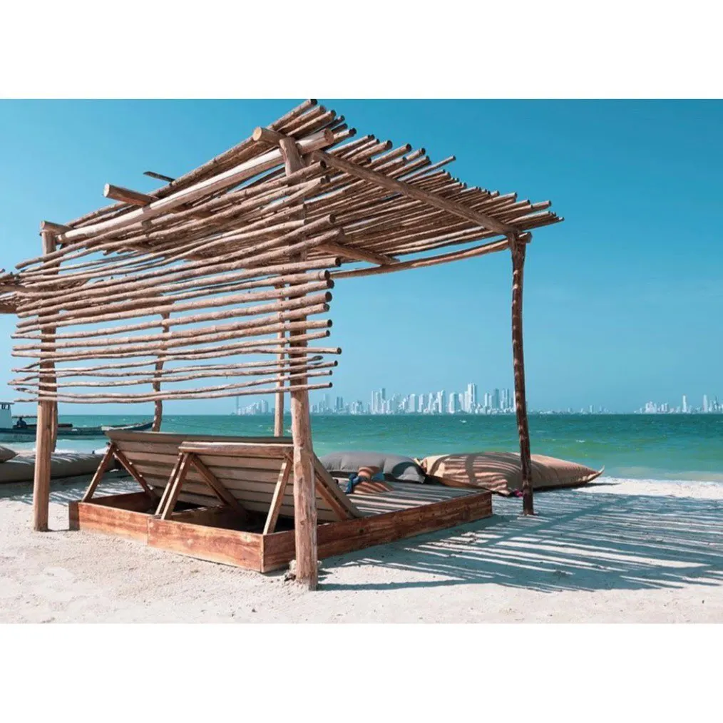 Wooden beach loungers on the sand with the Cartagena skyline in the distance