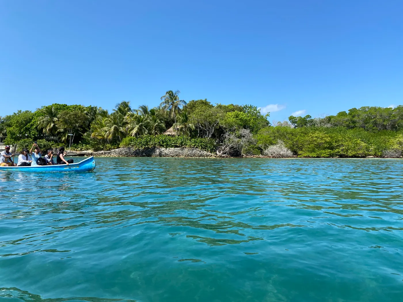 A canoe near an island in the turquoise water of the Rosario Islands